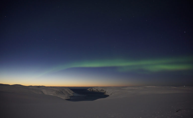 The sun has set in the west, and the Northern Lights are starting to appear over the Tufjord ©www.71-nord.no