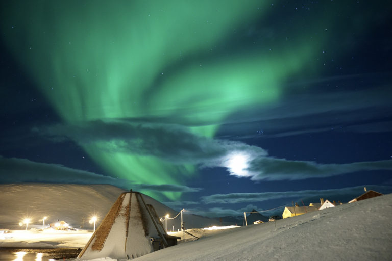 Northern Lights over Sarnes. Lavvus (tents) where king crabs are served in the middle, and then the old derelict boarding school over on the right. Sarnes is found on the land-facing side of Magerøya Island, and is much less exposed to bad weather ©www.71-nord.no